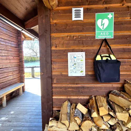 Hjärtstartare på vägg ovanför vedstapel