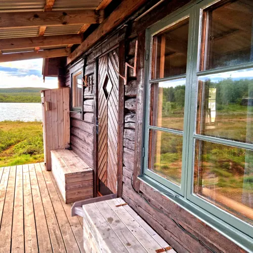 Snidad ytterdörr och fönster på stugans veranda