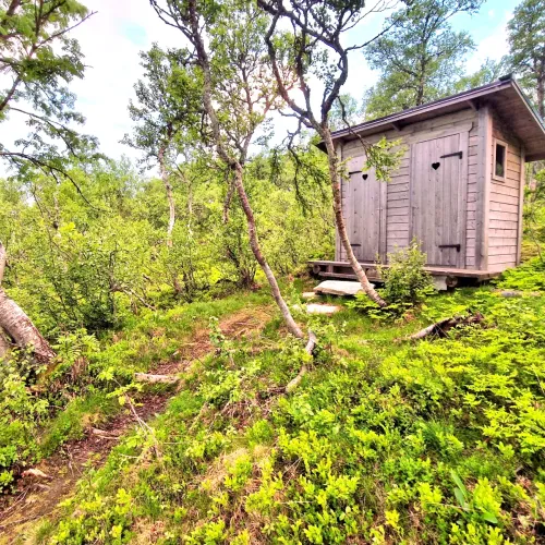 Timrat utedass med två bås i skogsbrynet