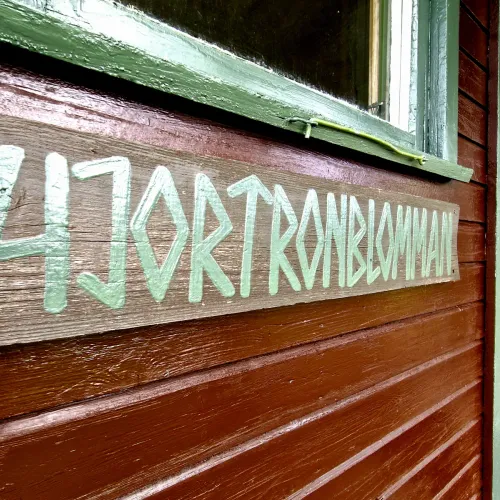 Handmålad skylt med stugans namn på timmerväggen