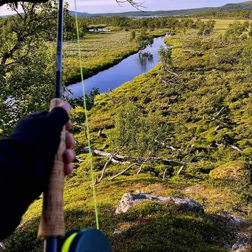 Utsikt över slingrande å från fjällhed, spö i förgrunden