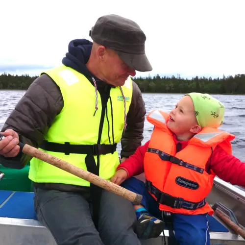 Man och barn i flytväst samspråkar i båten