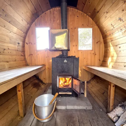 Tunnbastu med eldad kamin och vattenhink