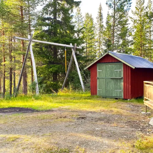Röd bod med grön dörr och gunga
