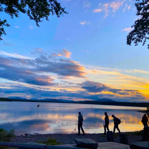 Siluetter av fiskare vid stranden i solnedgång