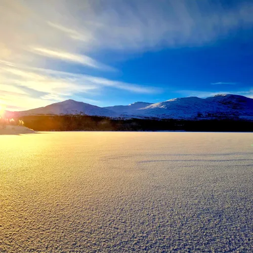 Soluppgång över snötäckt fjällsjö