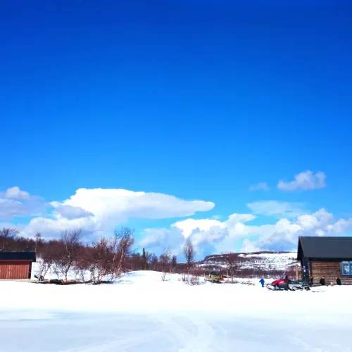 Stugor i vinterlandskap under blå himmel