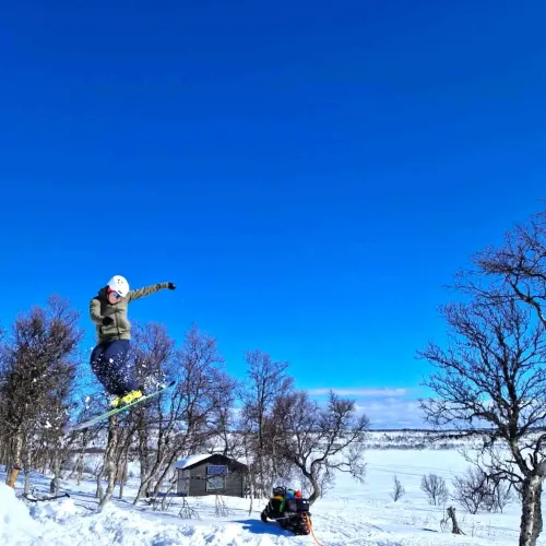 Skidåkare hoppar högt mot klarblå himmel