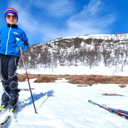 Pojke på längdskidor med fjällsluttning bakom
